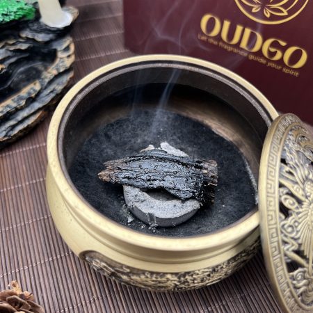 Dark wood fragment heating over charcoal in a ceramic burner