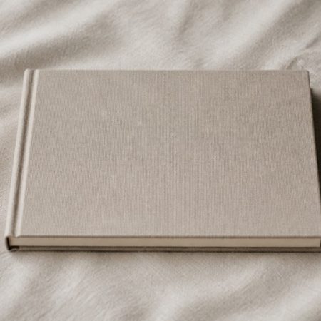 Blank closed linen-bound sketchbook on soft neutral fabric