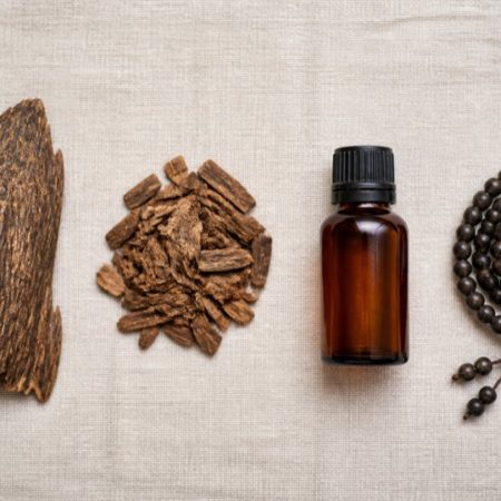 Natural wood, small chips, an unlabelled amber bottle and plain dark beads arranged separately on neutral linen