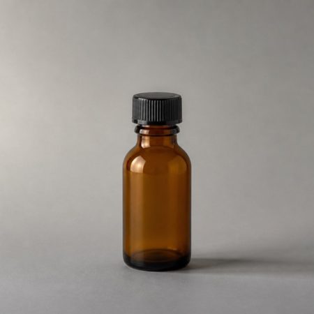 Single plain empty amber glass bottle on a warm-gray surface