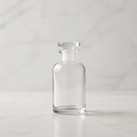 Single plain empty clear-glass bottle on a pale stone surface