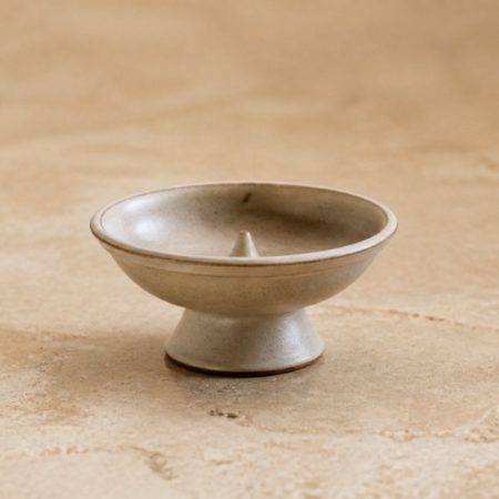 Plain unlabelled ceramic incense burner on a warm stone surface