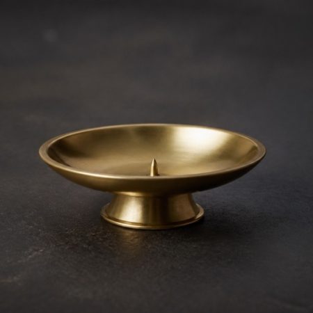 Plain unlit unlabelled brass incense holder on a dark neutral surface
