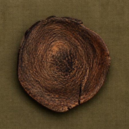 Single unlabelled natural wood disc on muted olive linen