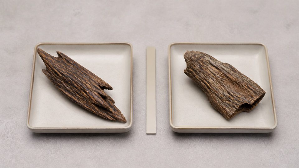 Two plain ceramic trays holding differently shaped natural wood fragments.